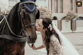   Outside Savignano Church in Italy, the bride kisses the carriage horse she adores that reflects her passion for horses.